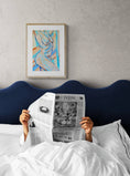 Load image into Gallery viewer, a person laying in bed reading a newspaper
